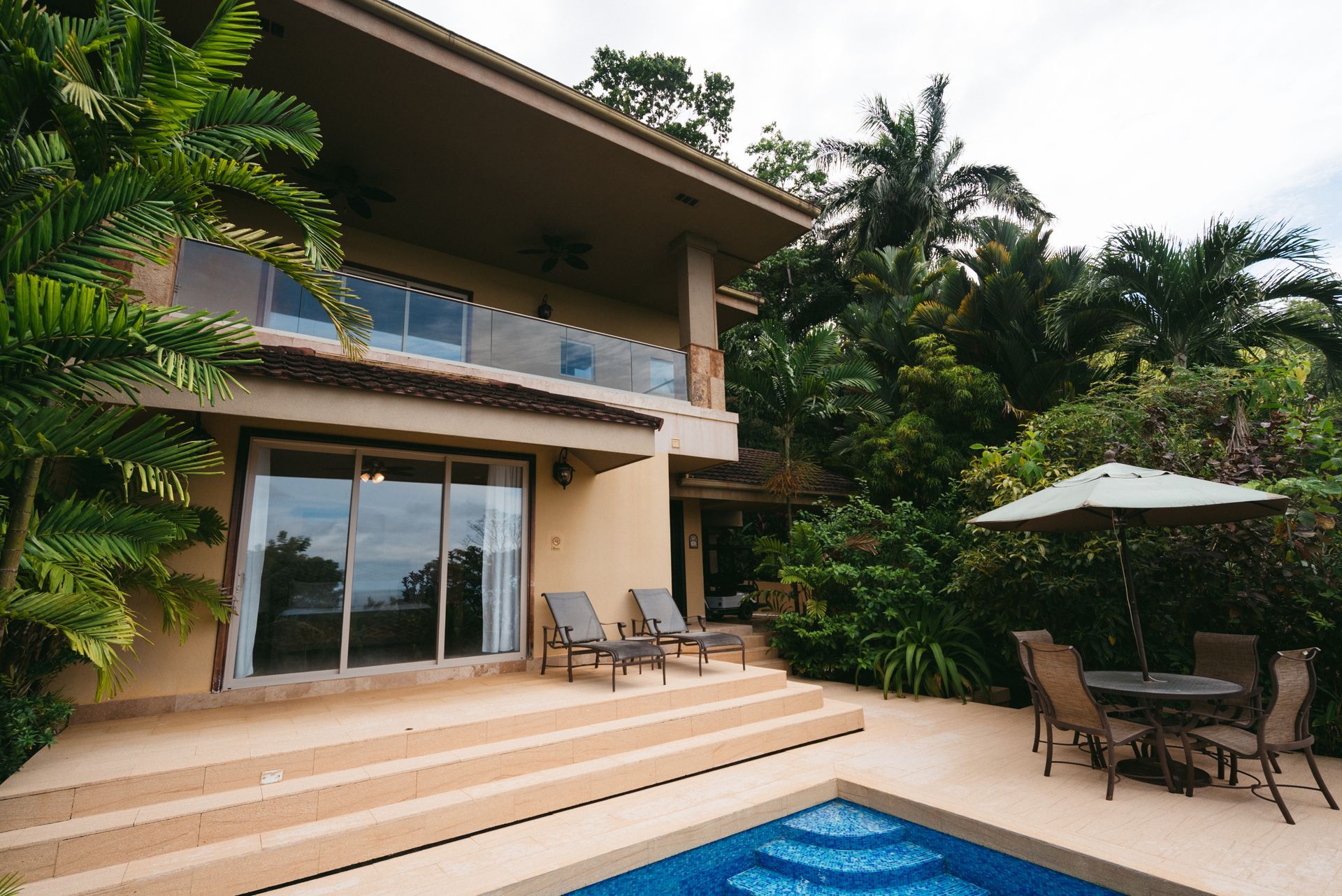 A living room with a couch , chairs , a table and a view of the ocean.