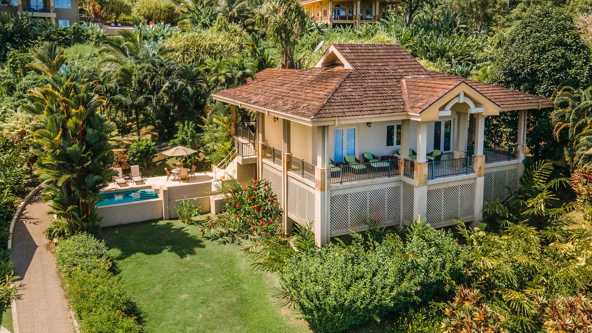 A living room with a couch , chairs , a table and a view of the ocean.