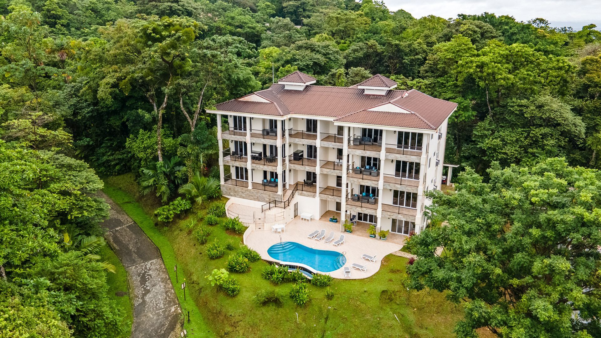 A living room with a couch , chairs , a table and a view of the ocean.