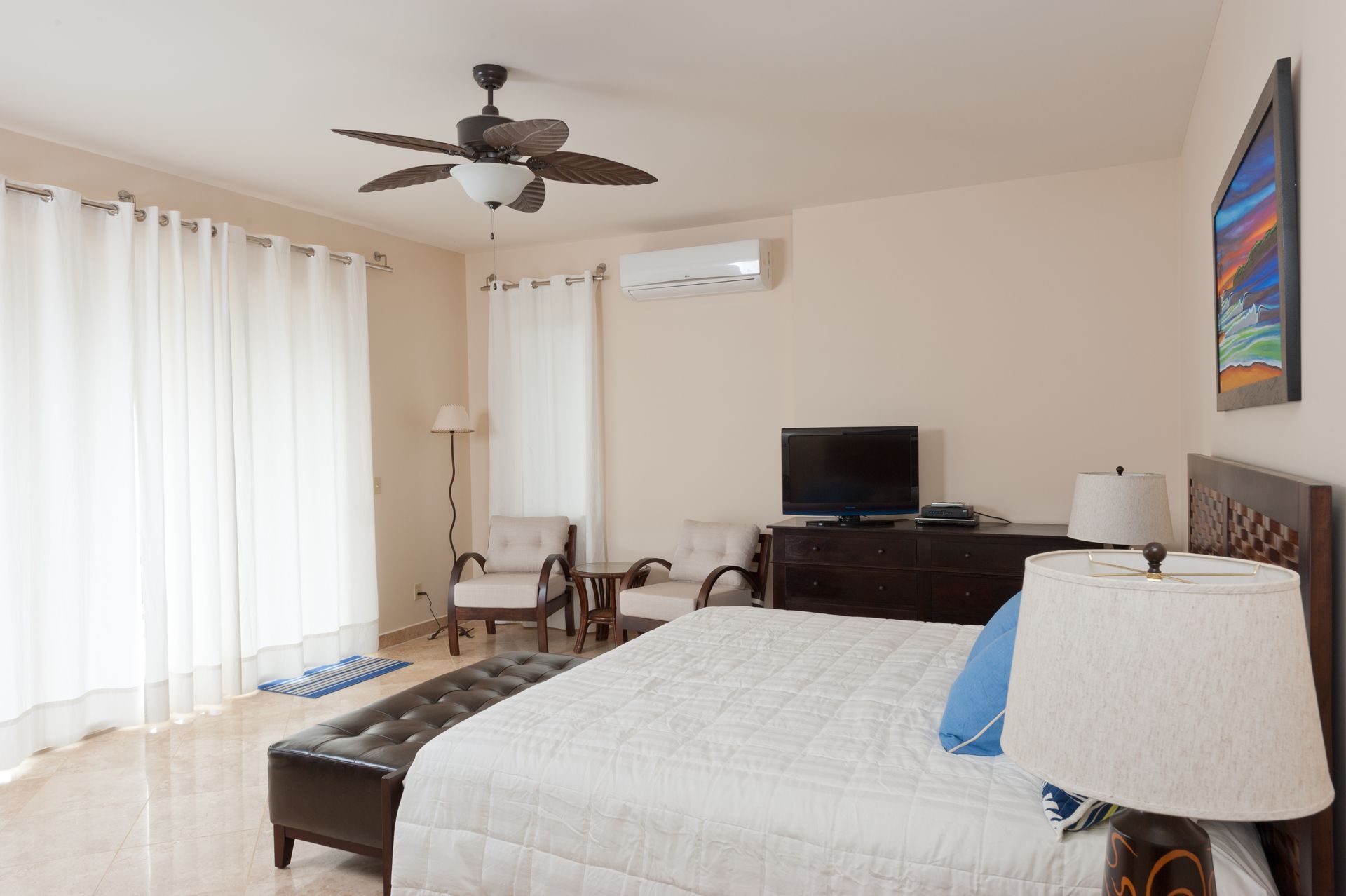 A bedroom with a large bed and a ceiling fan