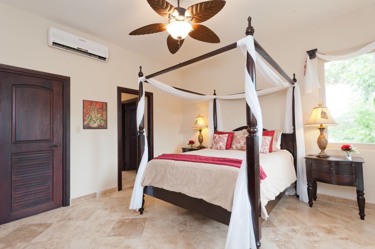 A bedroom with a canopy bed and a ceiling fan