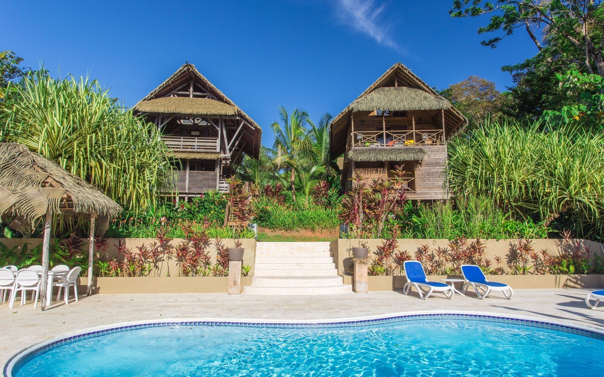 There is a large swimming pool in front of two houses.
