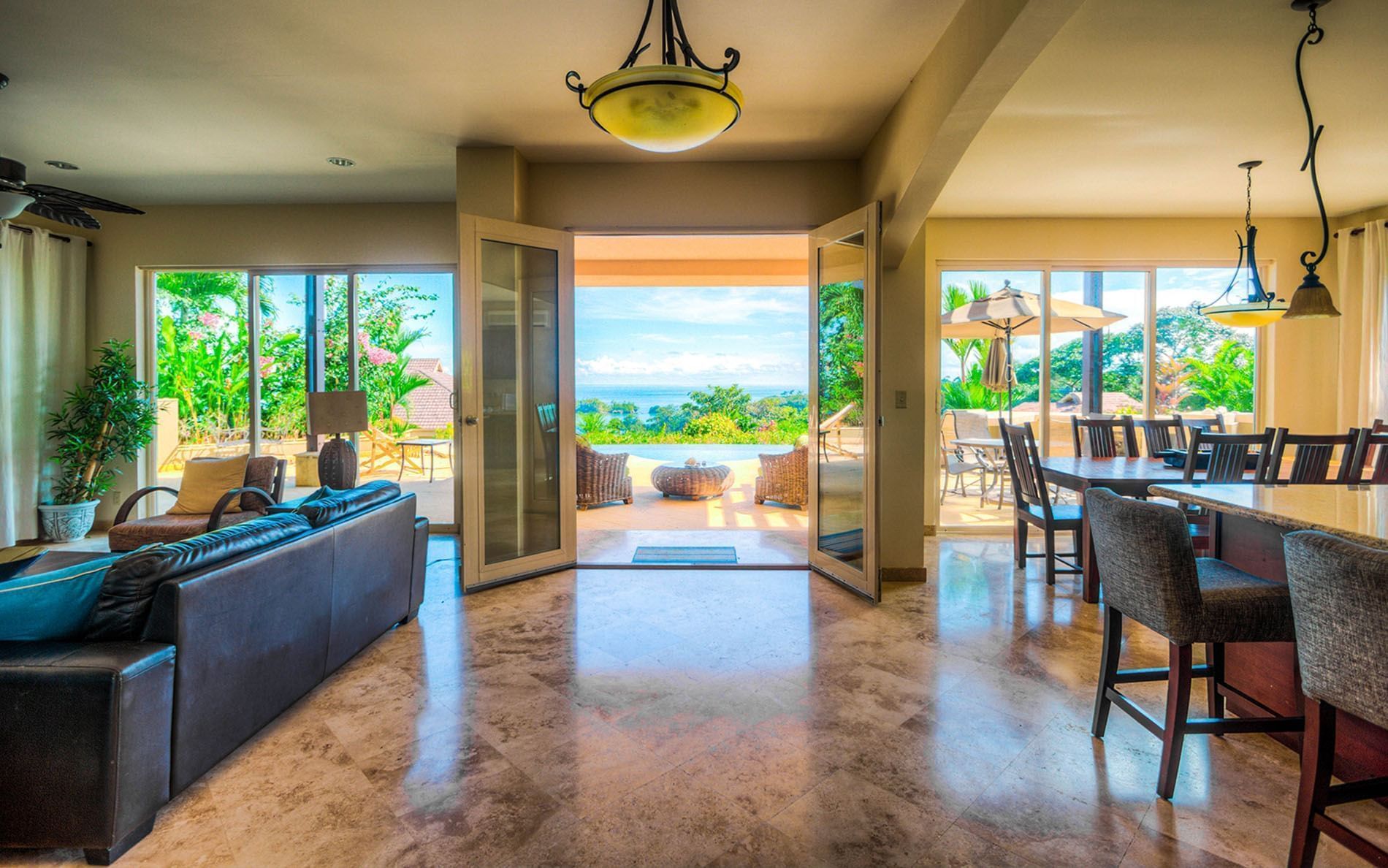 A living room with a couch , table and chairs and a view of the ocean.