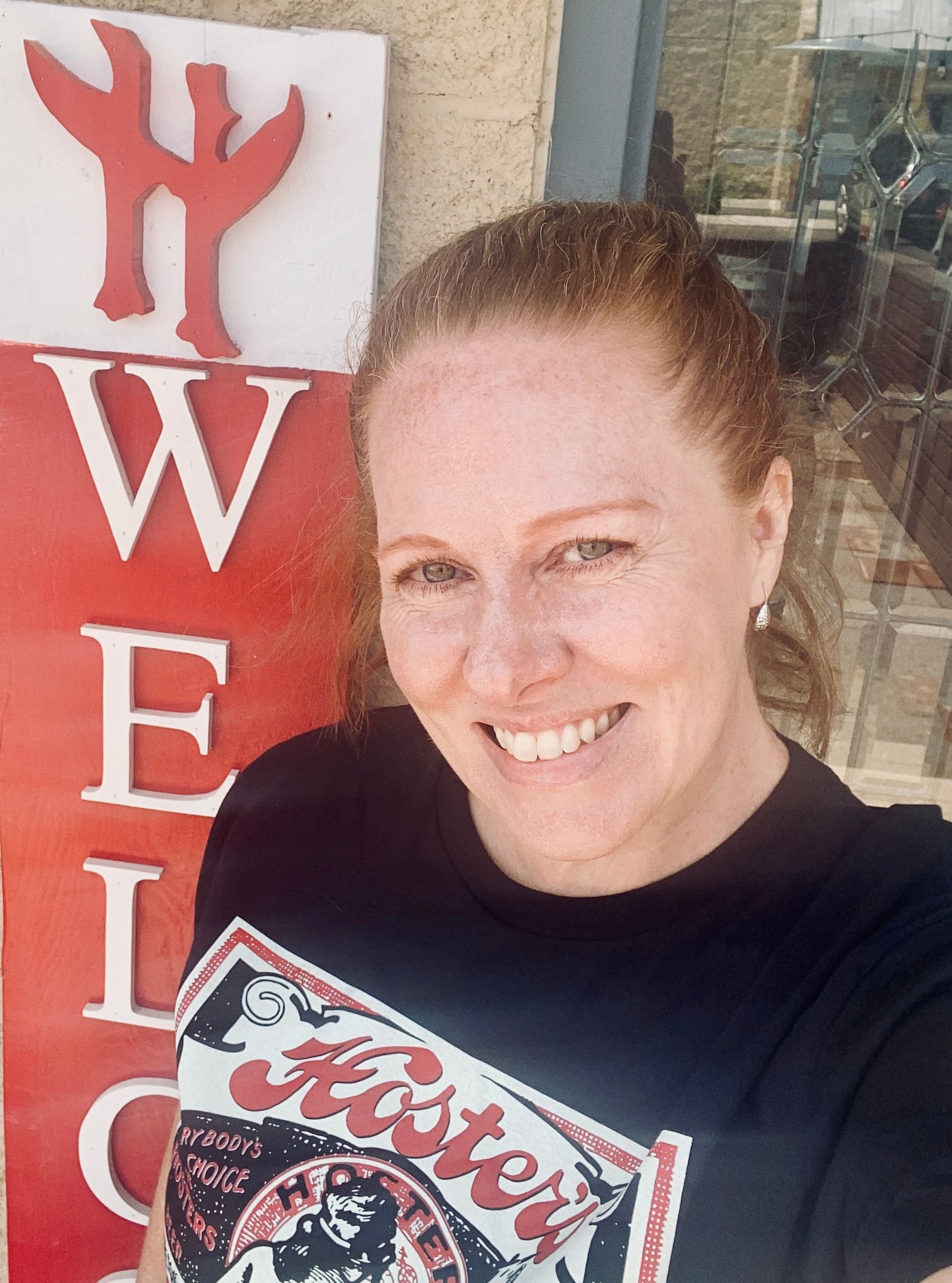 Sandy Hugill in front of Hoster welcome sign