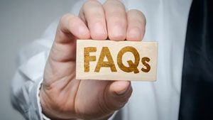 A hand in a white shirt holding a small wooden block engraved with the text 