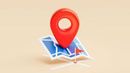 A 3D red location pin icon resting on a small, stylized blue and white map with a tiny red flag marker.