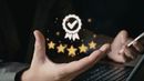 A person holds a digital icon of a star-rated badge with a checkmark, symbolizing high quality or customer satisfaction.