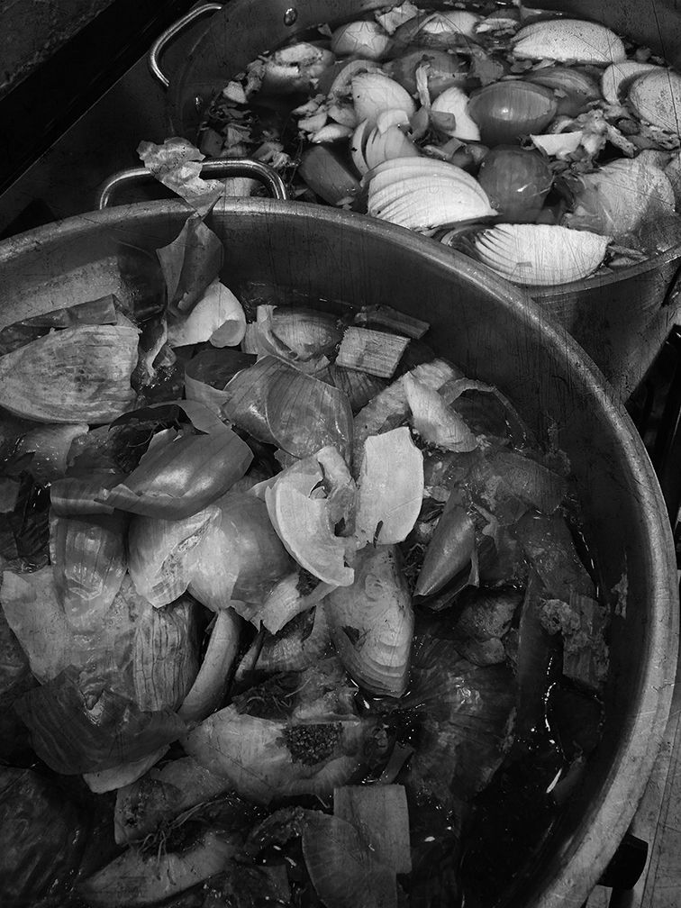 Two large metal stockpots filled with chopped vegetables and aromatics, preparing for a long simmer.