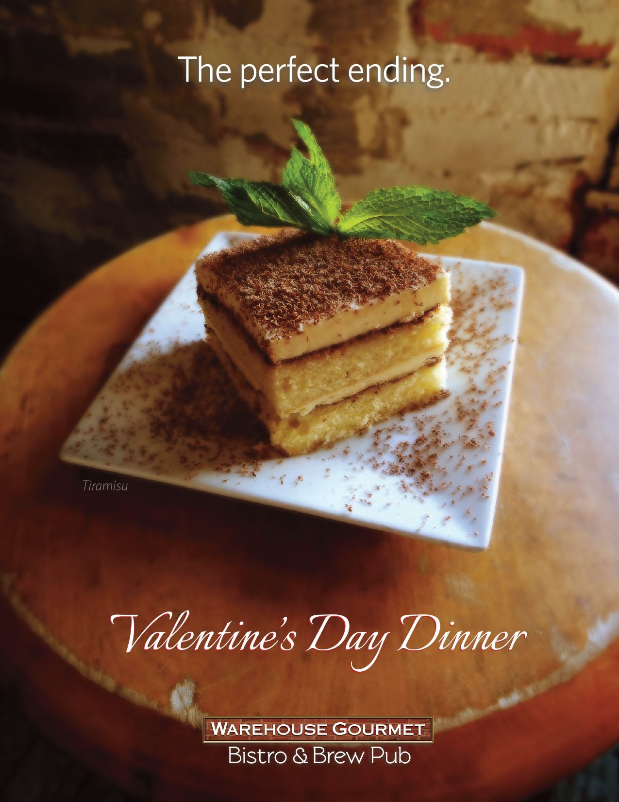A square serving of tiramisu topped with mint on a white plate, advertising a Valentine's Day dinner at Warehouse Gourmet.