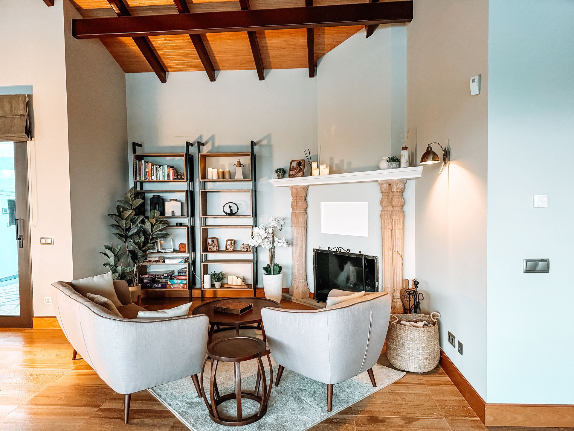 Living room with two armchairs, bookshelf, fireplace, and wooden ceiling.