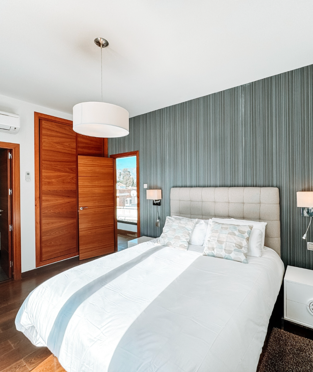 Bedroom with a bed, a wooden closet and door, and a striped accent wall.