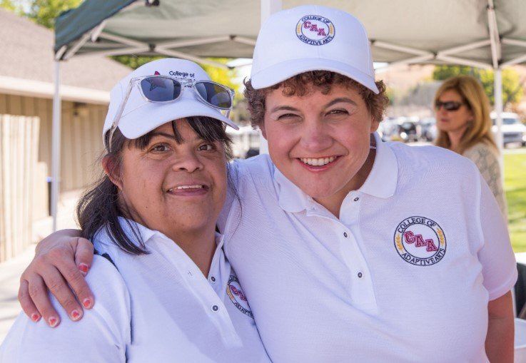 two women posing for a picture with one wearing a hat that says aaa