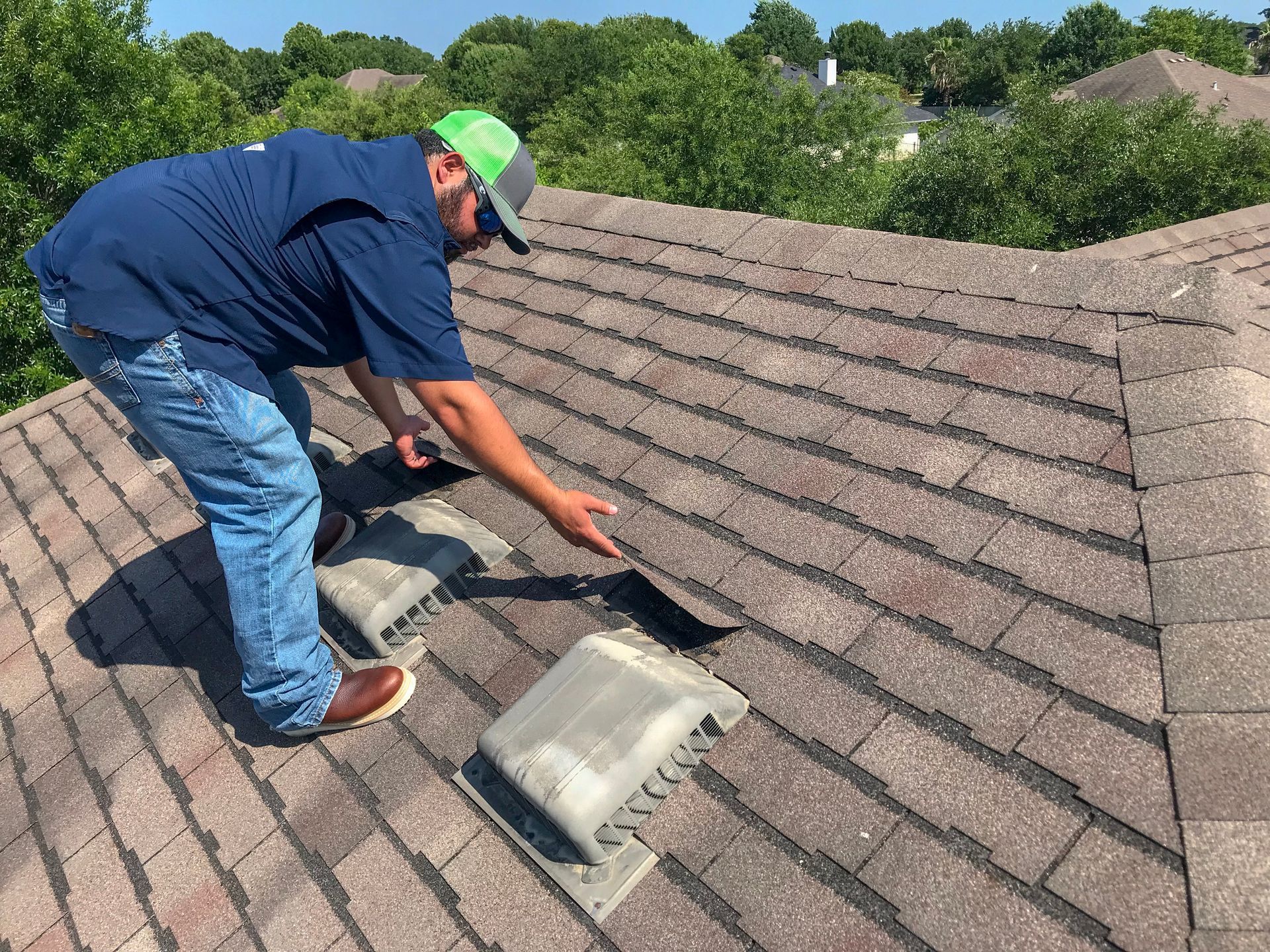 A man is standing on top of a roof looking at a hole in the roof.