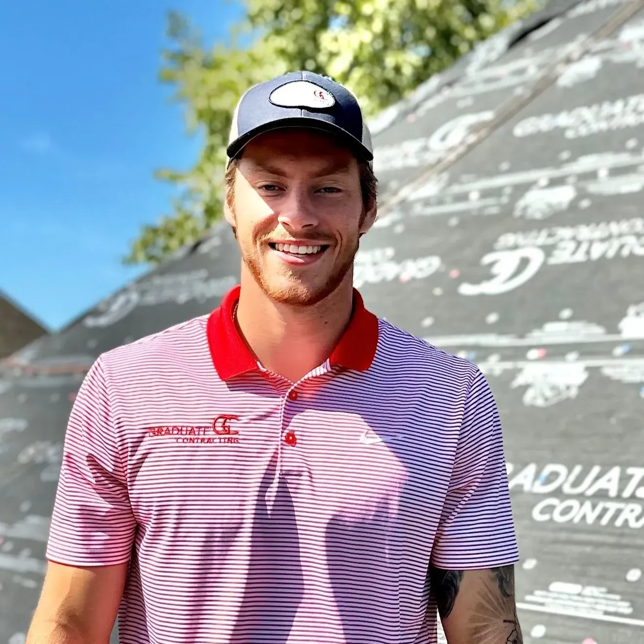A man wearing a red and white striped shirt and a hat is smiling.