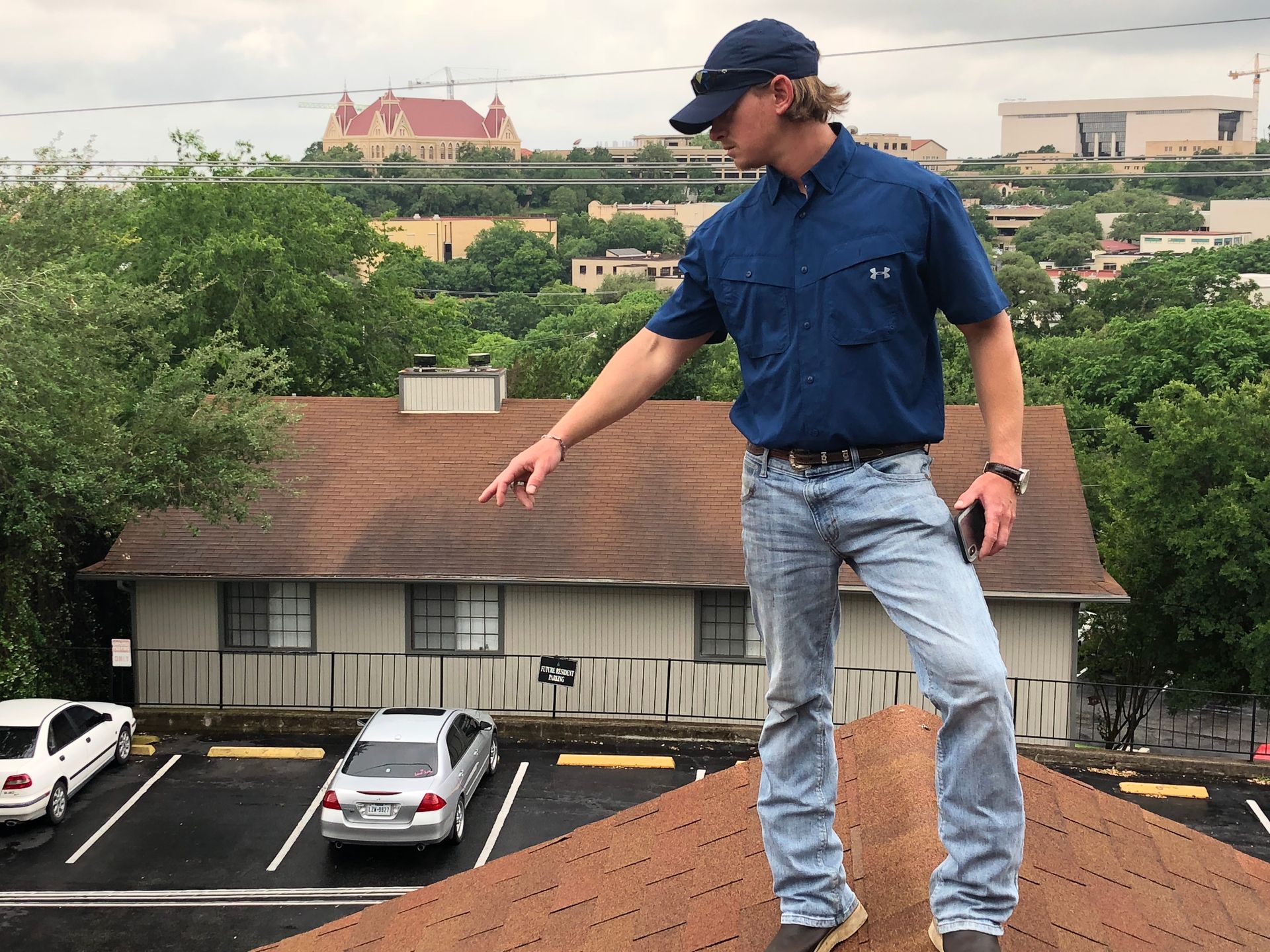 A man in a blue shirt is standing on the roof of a building