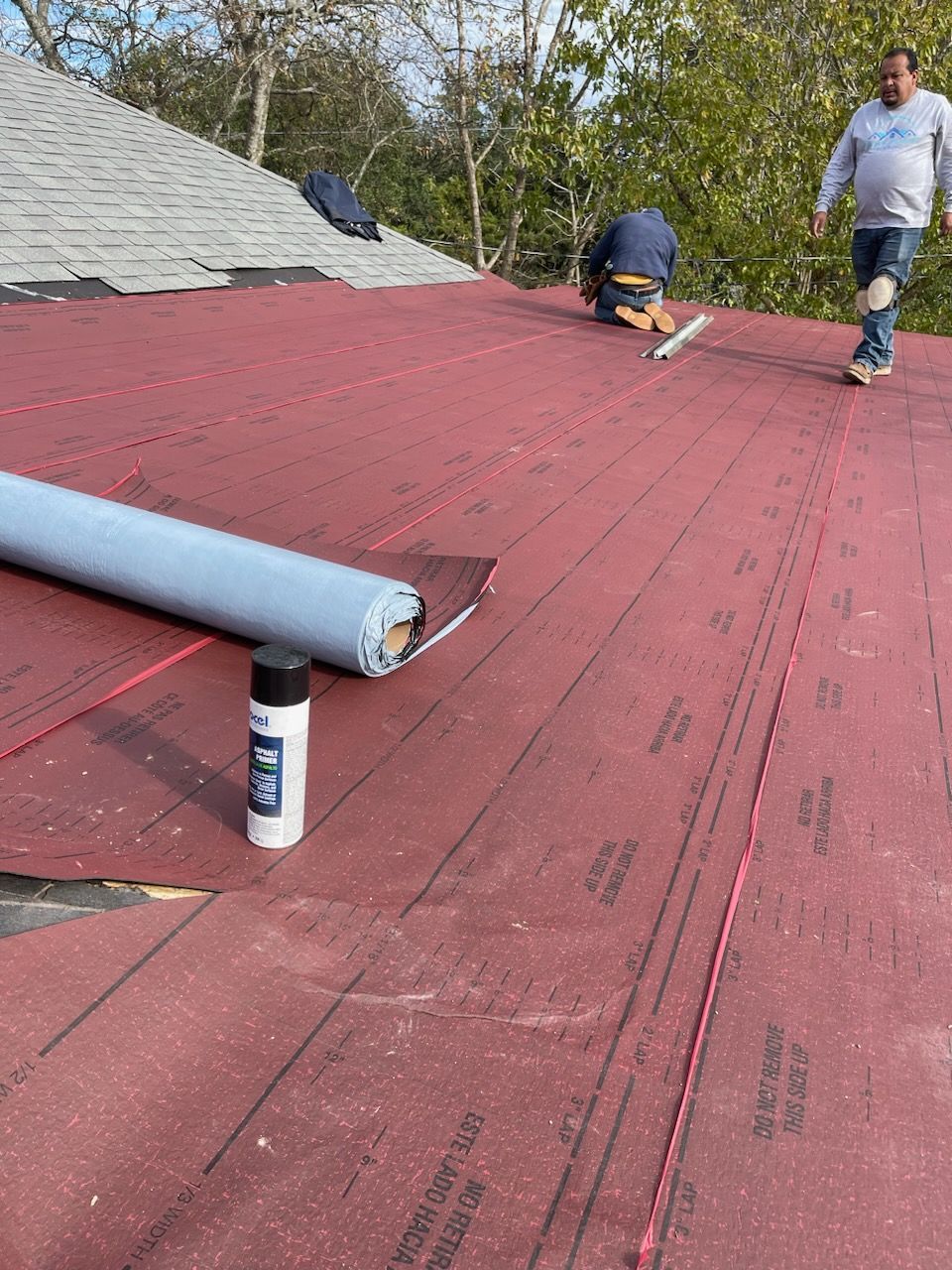 a man is standing on top of a red roof, base sheet for Bitumen