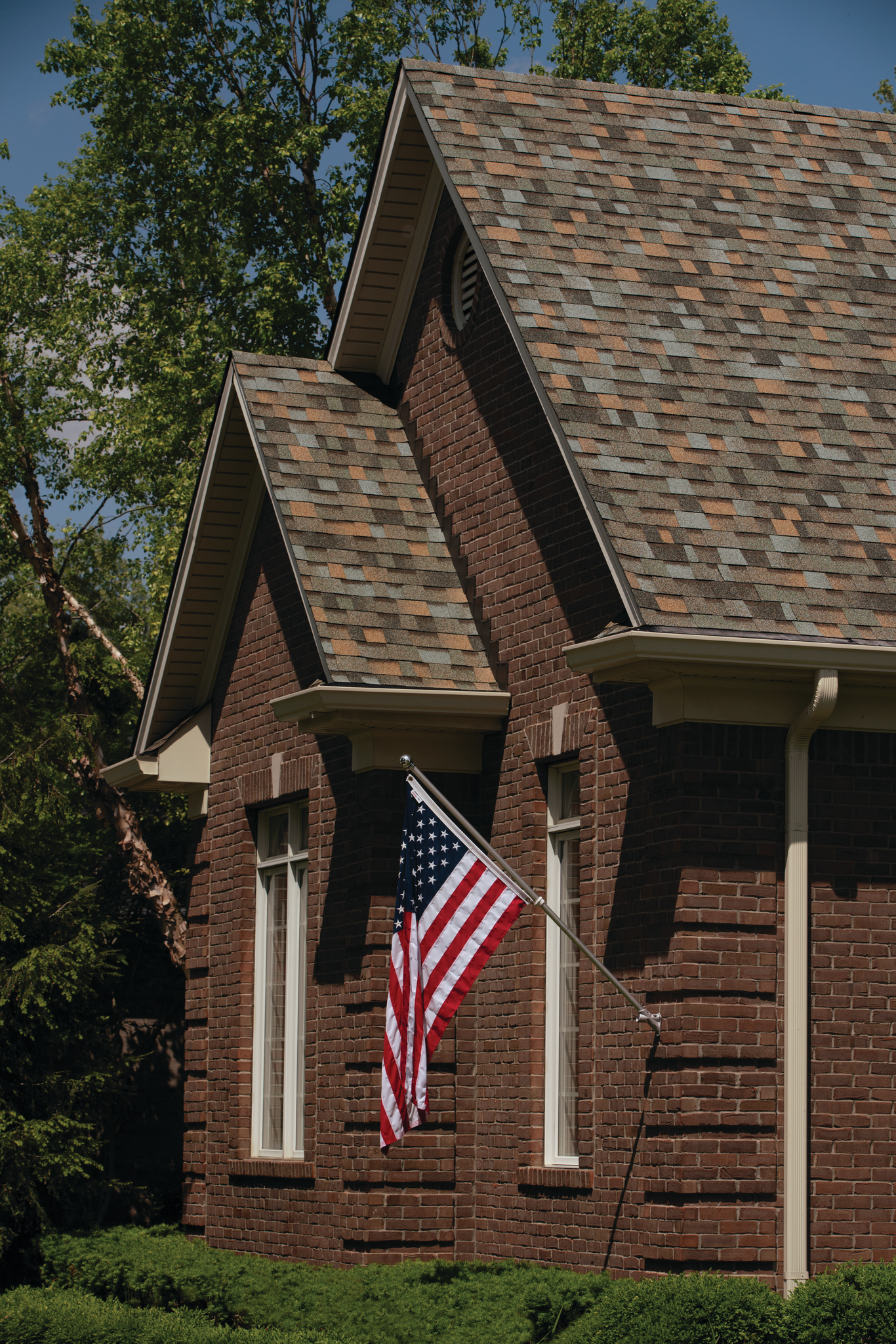 An american flag is flying in front of a brick house