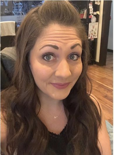A woman with long brown hair is smiling for the camera