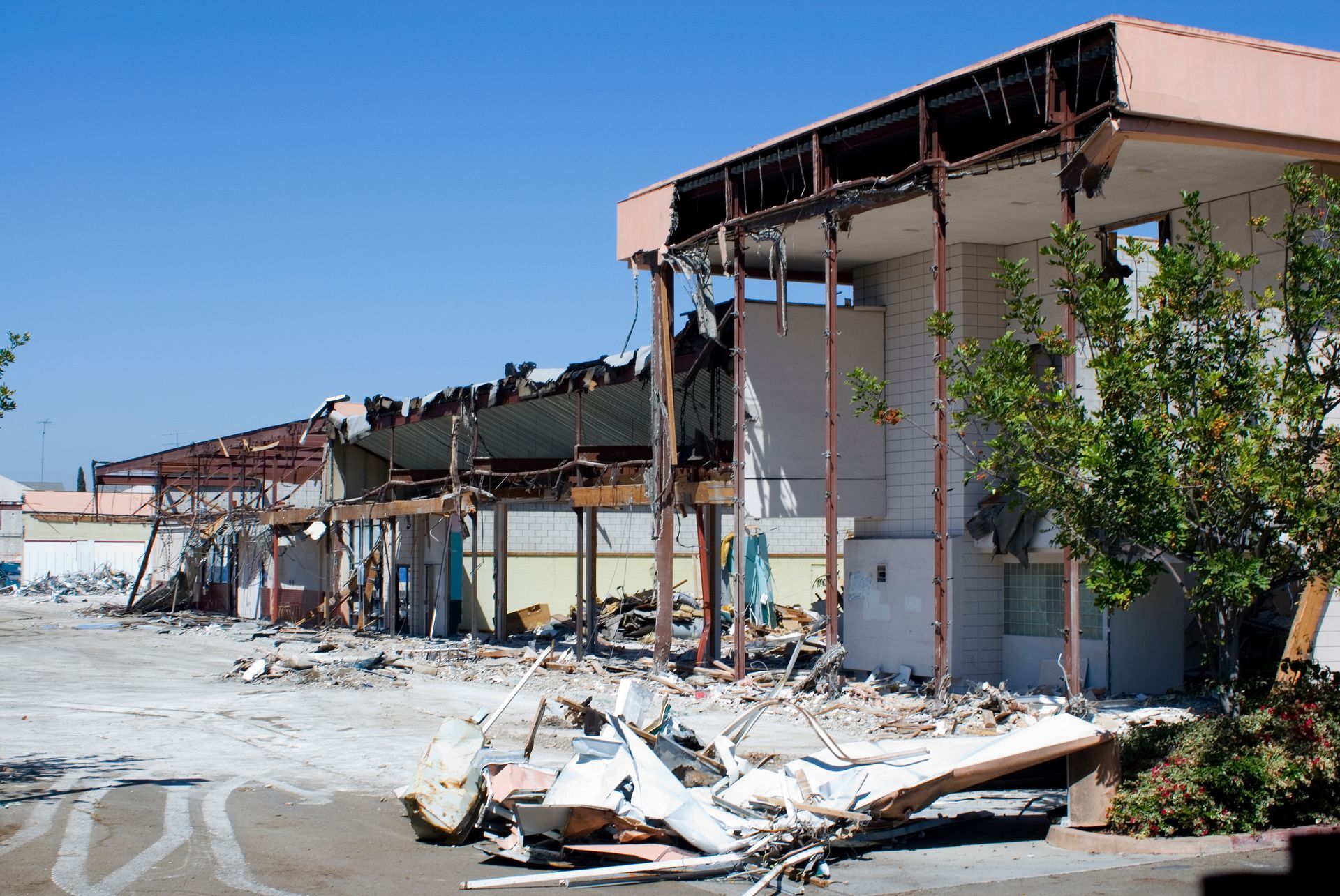 Building demolition; debris scattered, partially destroyed structure under a clear blue sky.
