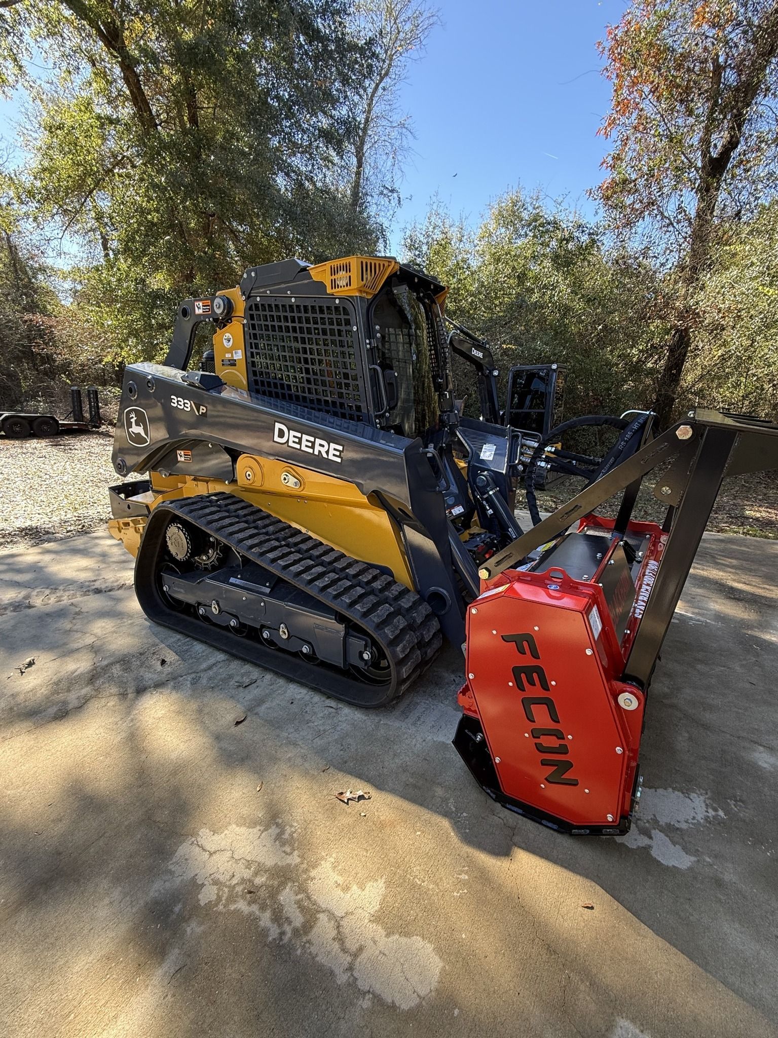 Yellow excavator clearing debris from a dirt field.