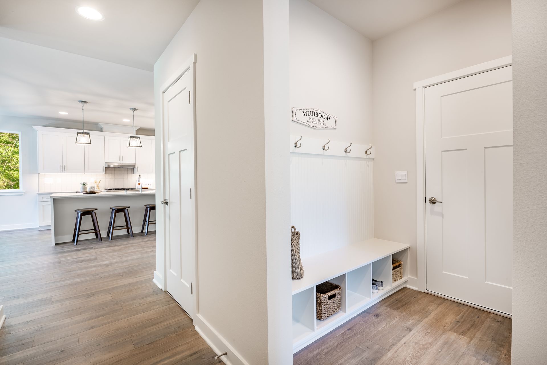 A hallway in a house with a bench and hooks on the wall.