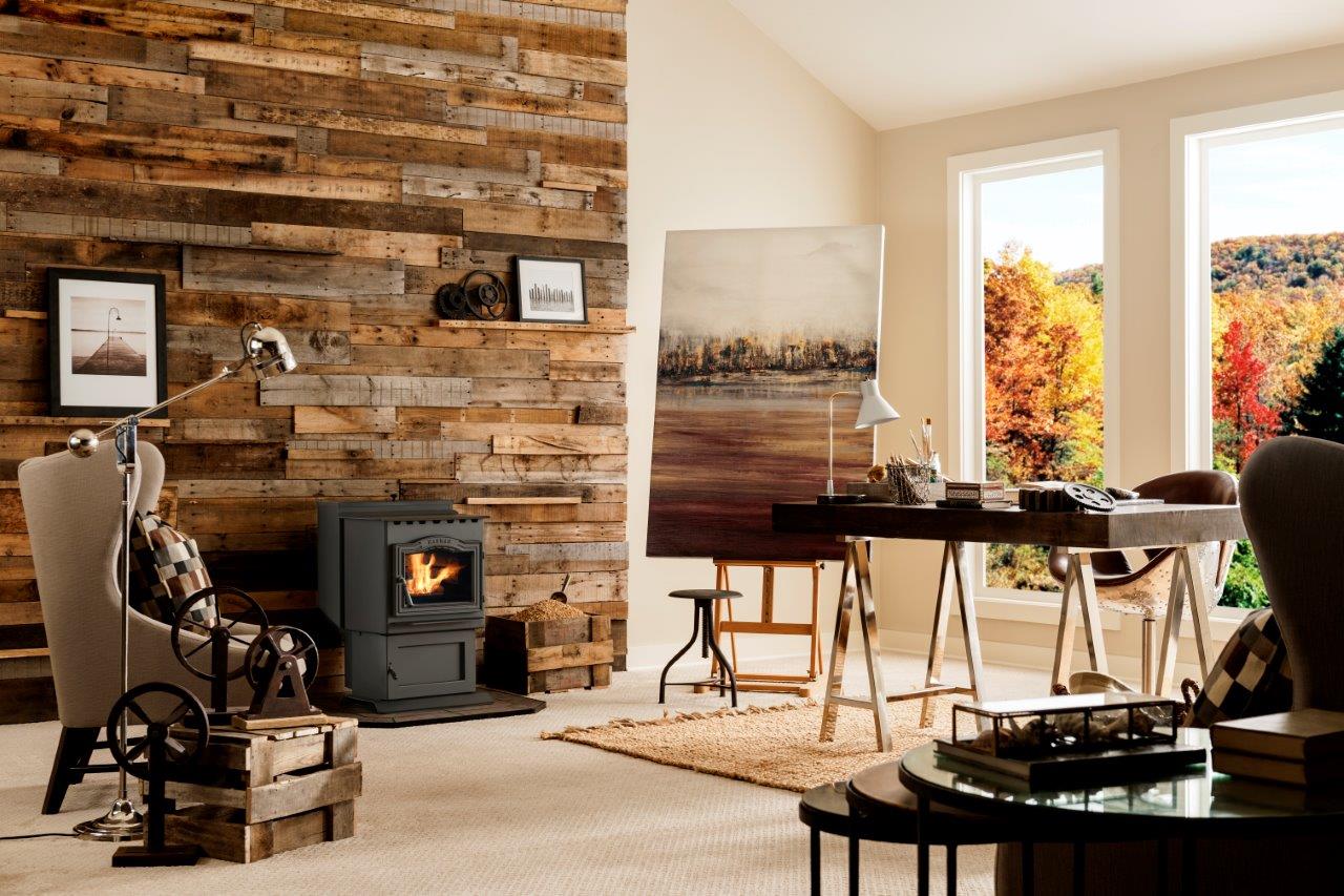 Cozy room with a rustic wood accent wall, featuring a burning stove and artwork with a vibrant fall view through the window.