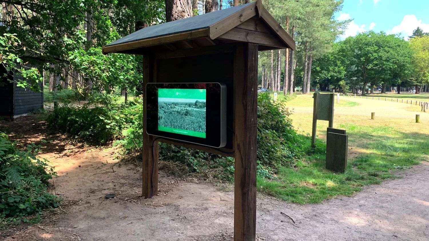 a wooden kiosk with a screen on it in a park .