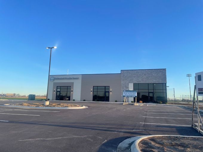 Modern, gray building with large windows, sign reads 