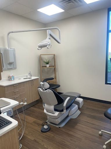 Dental operatory with chair, light, cabinetry, and window.