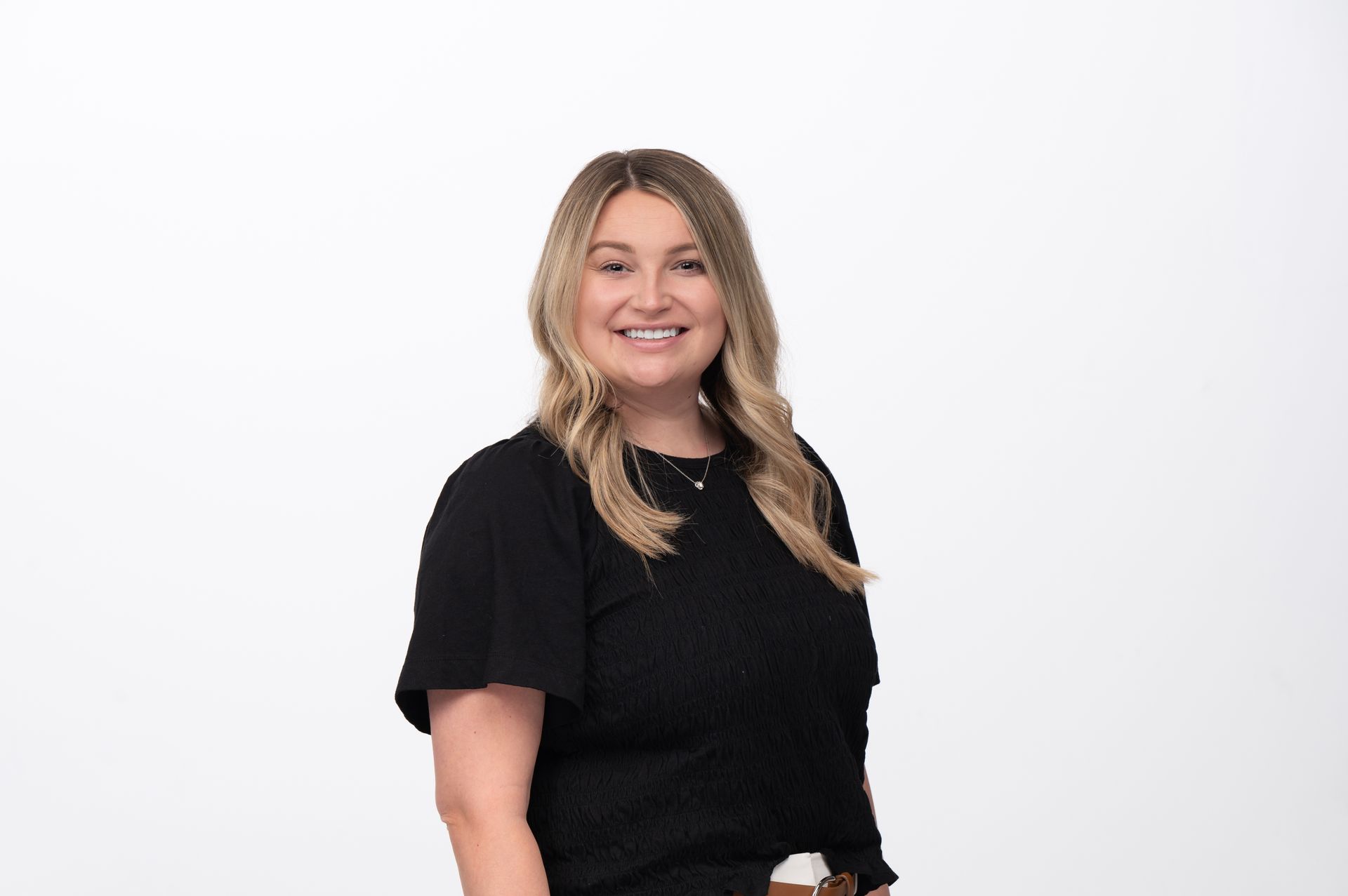 Woman with blonde hair, smiling, wearing a black shirt, white background.