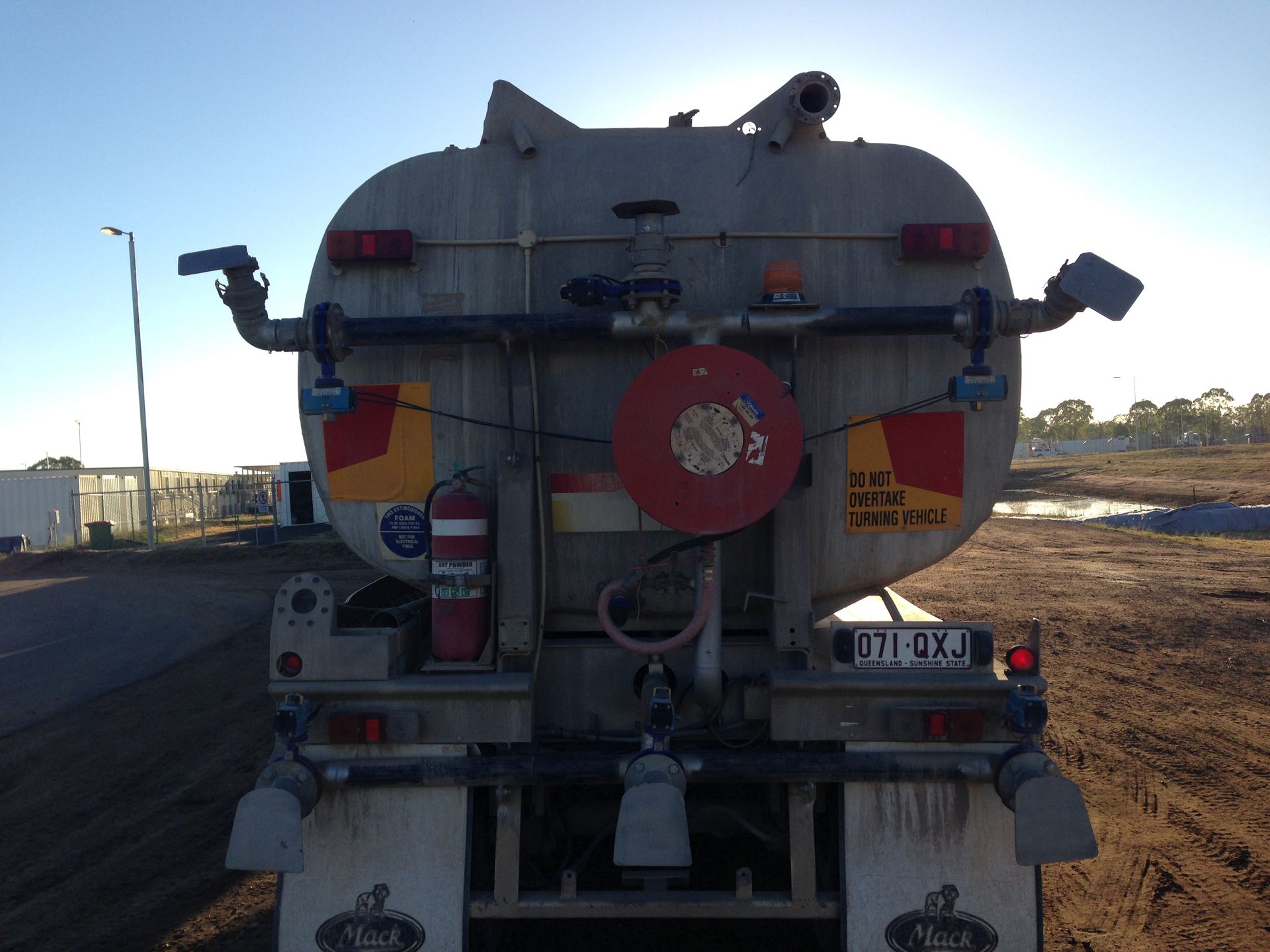 Rear view of a water tanker truck with spray arms, parked on dirt — Chewies Tipper Hire & Haulage in Gracemere, QLD