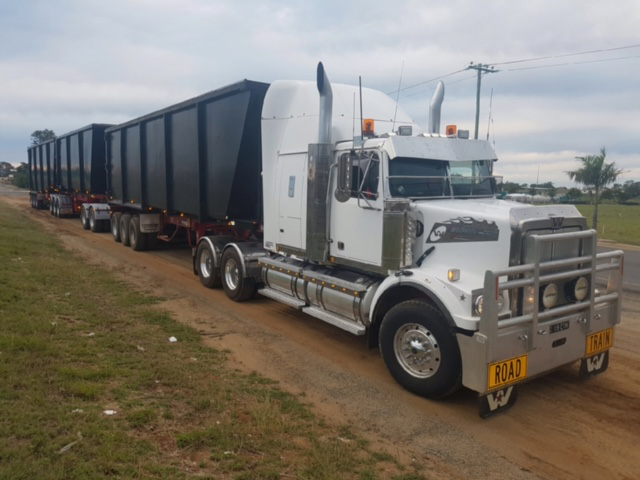 White semi-truck with black trailers parked on dirt road — Chewies Tipper Hire & Haulage in Gracemere, QLD