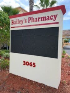 Bailey's Pharmacy sign with address 3065; features a blank black display.