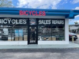 Bicycle shop storefront with a blue awning and neon 