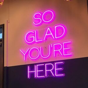 Pink neon sign on a wall that reads 