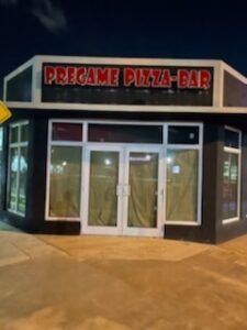 PreGame Pizza-Bar storefront with illuminated red sign above white double doors, surrounded by windows.