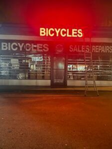 A bicycle shop at night with a lit-up 