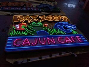 Neon sign for Razzoo's Cajun Cafe: frog and alligator, green grass, red and blue letters.