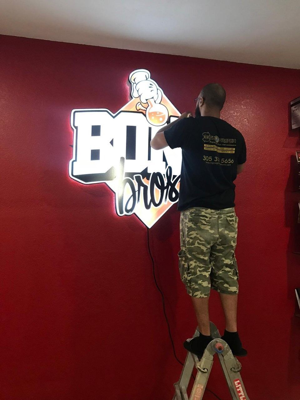 Man on a ladder installing illuminated 