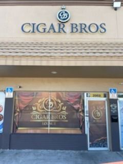 Cigar Bros storefront with signage. Brown awning, entrance, and window displays with logo.