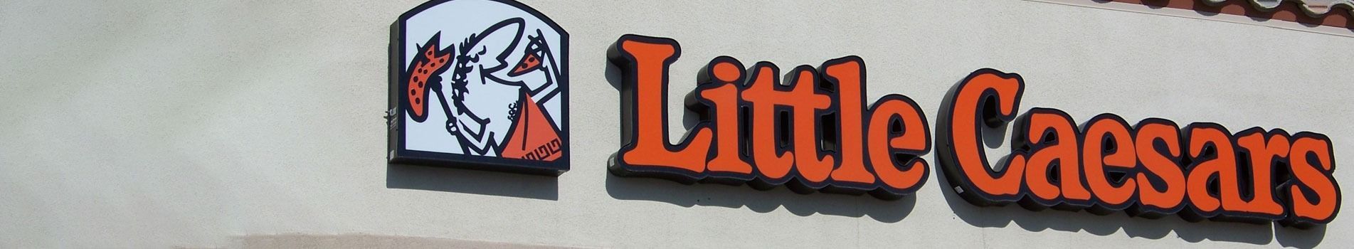 Little Caesars sign on a building, with logo of Caesar in the corner.
