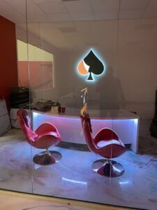 Two red, retro chairs face a desk with a glowing spade symbol in an office setting.