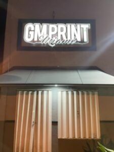 GM Print Miami sign above a building with closed blinds.
