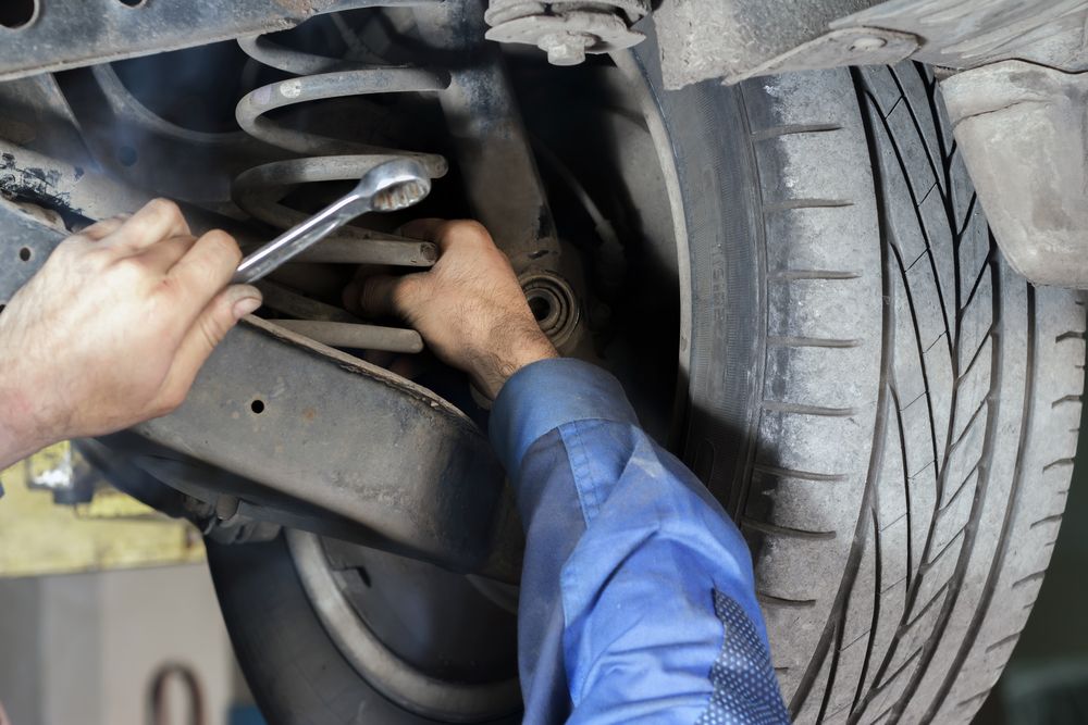 Mechanic Working On Car Suspension, Using Wrench Near A Tire — Britek Automotive in Bentley Park, QLD