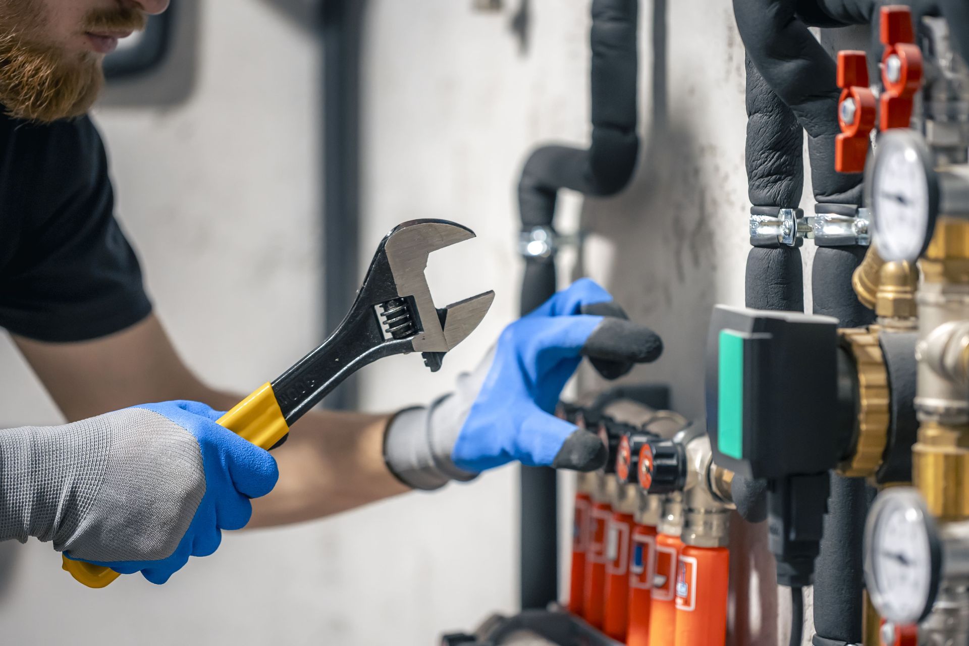A man is working on a pipe with a wrench.