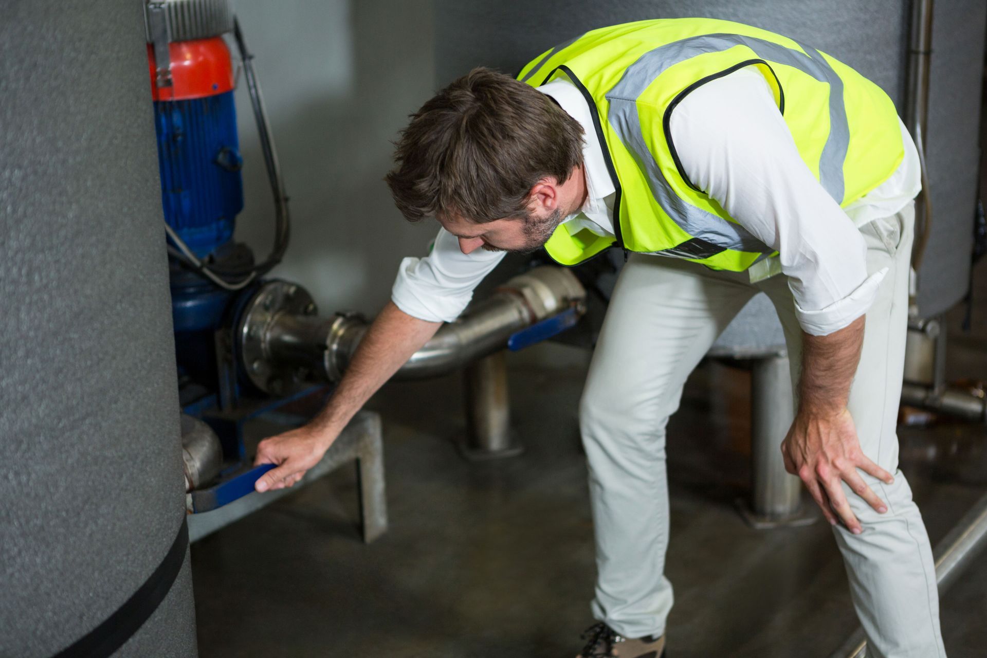 A man is kneeling on the floor measuring a piece of wood.