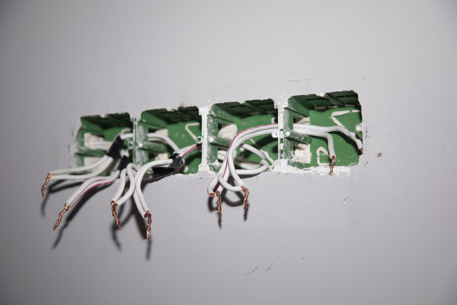 A hole in a wall with electrical wires coming out of it.