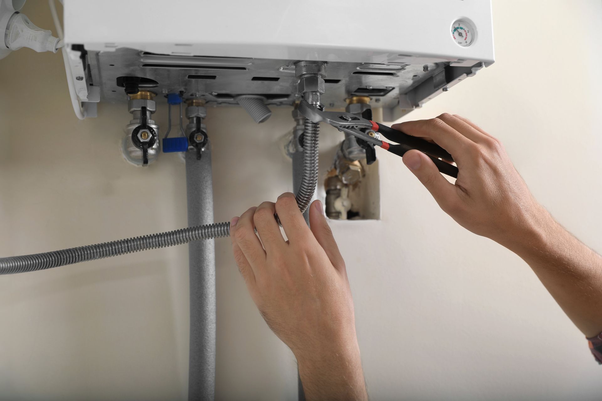 A person is fixing a boiler with a pair of pliers.