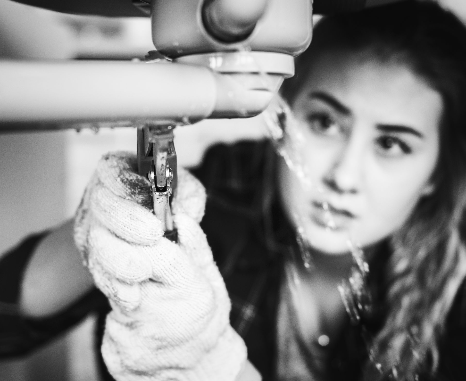 A woman is fixing a sink with a wrench.