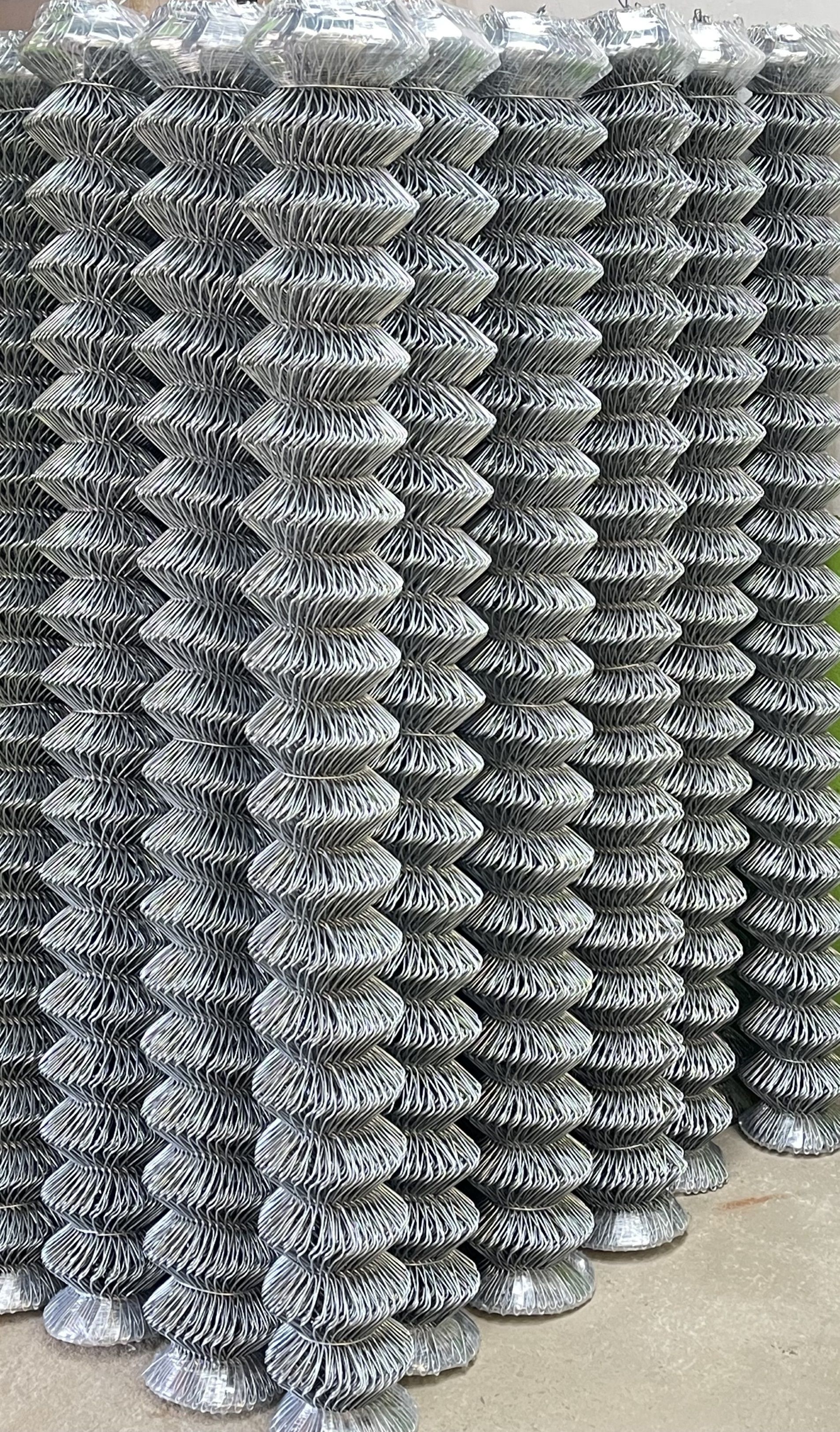 Una valla de alambre está rodeada de césped y árboles.